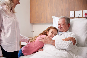 Wall Mural - Granddaughter Hugging Grandfather On Family Hospital Visit