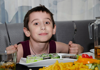 Little boy with Cutlery eating a variety of dishes