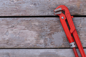 Wall Mural - Adjustable red pipe wrench on wooden background. Adjustable wrenches on wooden boards with copy space.