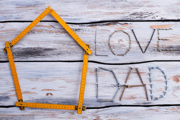 Wall Mural - LOVE DAD text on wooden background. Folding ruler in a shape of house and inscription LOVE DAD. Flat lay composition.