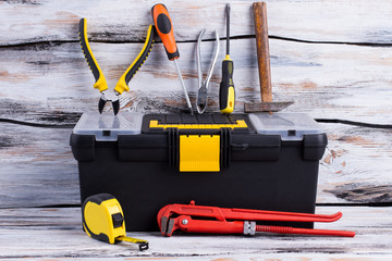 Tool box and various tools on wooden background. Adjustable wrench, tape measure, screwdriver, pliers, hammer and tool box.