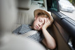 Junge mit Hut schläft auf dem Rücksitz im Auto