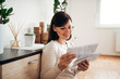 © bnenin - Beautiful woman looking at mail at cozy home.