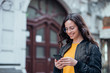 © bnenin - Positive young woman walking in the city at looking at smart phone.
