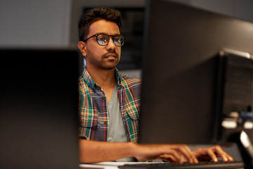 deadline, technology and people concept - close up of creative man in glasses working at night office and thinking