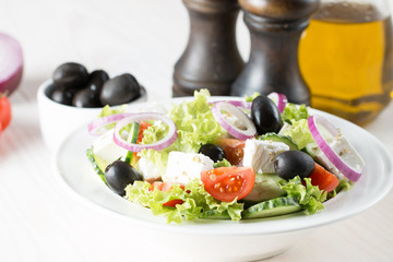 Fresh healthy salad with delicious ruccola, spinach, cabbage, arugula, feta cheese, red onion, cucumber, sesame seeds and cherry tomato on wooden background. Healthy and diet food concept.