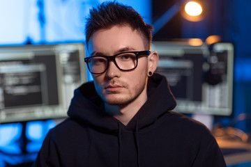 Poster - cybercrime, hacking and technology concept - young asian hacker wearing glasses and hoodie in dark room with computers at night