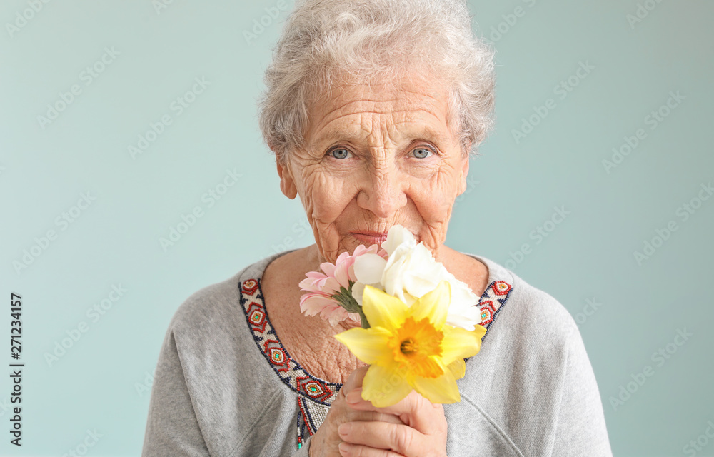 Portrait of senior woman with bouquet of flowers on grey background - obrazy, fototapety, plakaty 