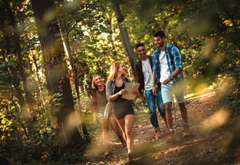 group of four friends having fun hiking through forest together.