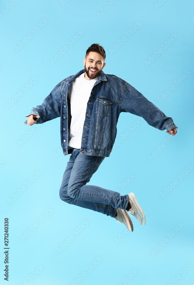 Jumping young man in jeans clothes on color background