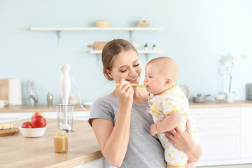 mother feeding her little baby in kitchen at home