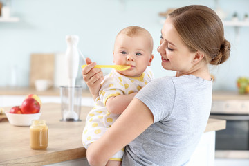 Sticker - Mother feeding her little baby in kitchen at home