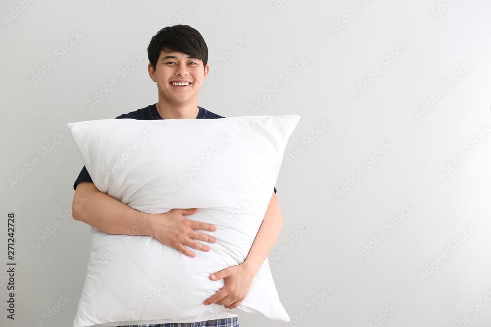 Handsome young man with pillow on white background