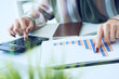 © cameravit - A woman's hand pointing on summary report chart and calculate finance in office close-up.