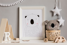 Stylish And Cozy Childroom With White Mock Up Photo Frame, Wooden Accessories And Toys, Koala Bear, Rattan Basket And White Garland And Stars On The Gray Wall. Bright And Sunny Interior. Template, 