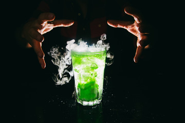 Barman`s hands showing smoking green cocktail