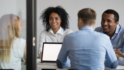 Multiracial businesspeople sitting in boardroom, discussing project, strategy