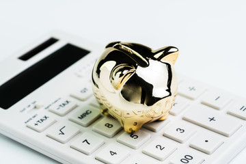 Budget, cost or investment calculation and financial activity concept, golden shiny piggy bank wearing glasses on white calculator on white background