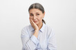 © shurkin_son - Frustrated female pensioner in blue shirt holding hand on her face having worried uneasy facial expression, thinking about her future. Unhappy sad senior woman suffering from terrible toothache