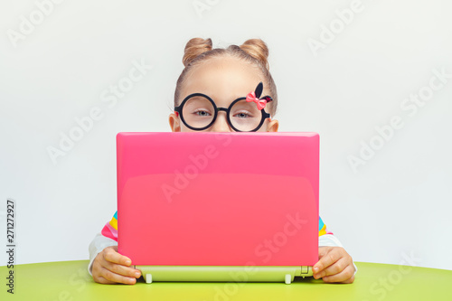 Photo beautiful cute little girl behind laptop computer looking at camera