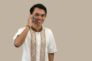 portrait of Muslim youth posing in Muslim attire standing in front of the camera, looking attentive with a smile on the screen