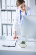 © lenets_tan - Young woman doctor at work while pointing at computer in hospital office.