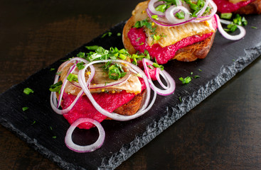 Smoked salmon sandwich laid out on a black slate.