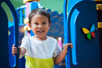 Smiling young boy holding on from a kids playground jungle gym with an excited look and ready to have fun.