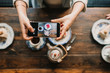 © Westend61 - Top view of woman taking a photo of cake and tea in coffee shop
