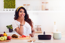 Beautiful Young Woman Preparing Meal, Biting A Vegetable During Cooking