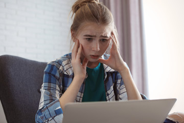 Wall Mural - Shocked teenage girl with laptop indoors. Danger of internet