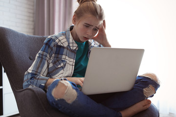 Wall Mural - Shocked teenage girl with laptop indoors. Danger of internet