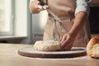 © New Africa - Female baker preparing bread dough at table, closeup