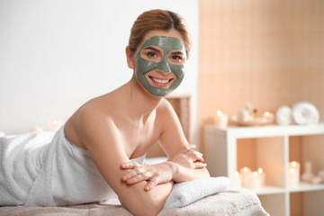 Beautiful woman with mask on face relaxing in spa salon. Space for text