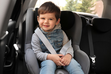 cute little child sitting in safety seat inside car. danger prevention