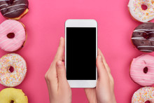 Partial View Of Woman Holding Smartphone With Blank Screen Near Tasty Glazed Doughnuts On Bright Pink Background