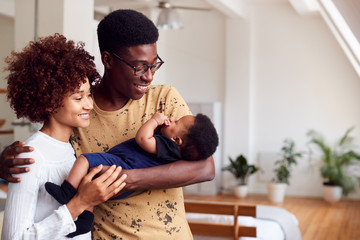 loving parents holding newborn baby at home in loft apartment