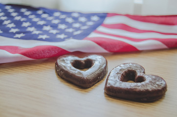 two heart shaped biscuits and usa flag on wooden table happy memorial day.