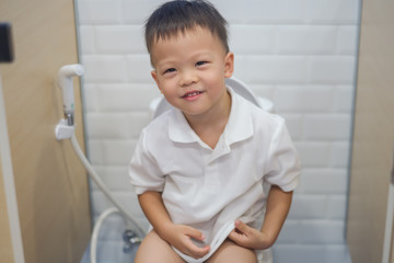 Wall Mural - Cute smiling Asian 2 - 3 years old toddler boy child sitting on toilet modern style, Little boy use public / school toilet for kids, Clean school washrooms, Potty Training, Learn to use Toilet concept