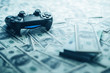 Concept of gaming addiction. Close up photo of gamepad on the money background.