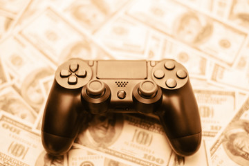 Wall Mural - Concept of gaming addiction. Close up photo of gamepad on the money background.