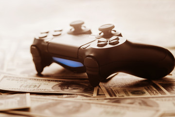 Canvas Print - Concept of gaming addiction. Close up photo of gamepad on the money background.