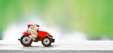 Small Red Tractor Model And White Meadow Flowers On Blurred Natural Background. Summer Season, Agriculture, Farming, Garden. Close Up. Copy Spase