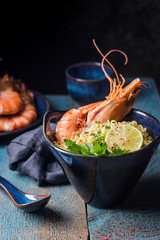 Wall Mural - A bowl of instant Chinese noodles with green onions, red hot chilli peppers, and shrimps on a dark rustic background