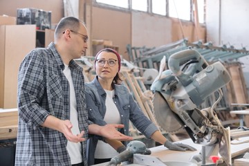 Wall Mural - Industrial portrait of two working men and woman, talking at machine tools