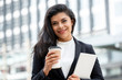 © Atstock Productions - Smiling Latino businesswoman holding coffee cup and tablet computer