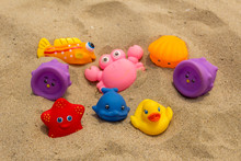 Colorful Rubber Toys On Sand Beach At The Seaside.