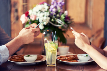 Wall Mural - Midsection of couple texting in restaurant