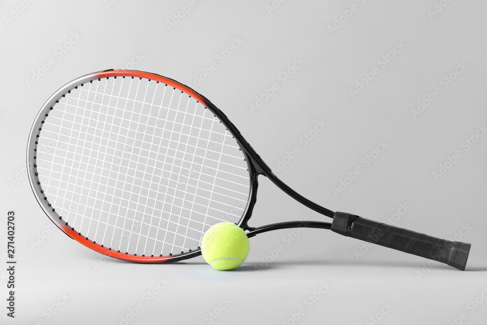 Tennis racket and ball on grey background