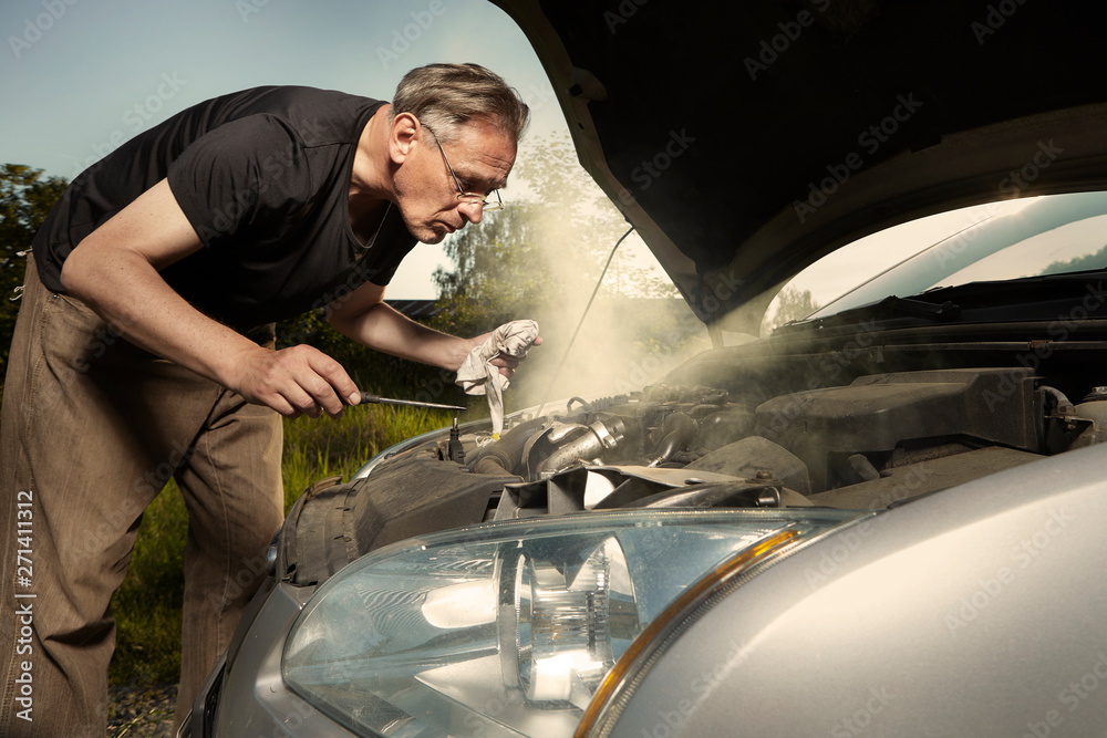 Aging man trying to fix broken car engine on lonely way - obrazy, fototapety, plakaty 